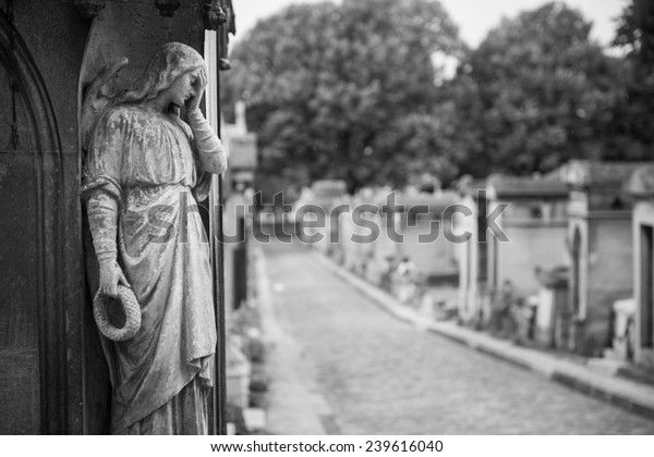 Statue looks on at Pere Lachaise Cemetery in Paris, France