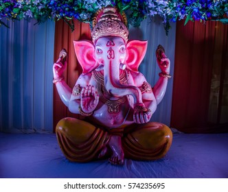 A statue of lord Ganesha under colourful lights.