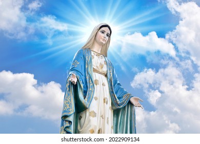 Statue of Our lady of grace virgin Mary with Bright Blue Sky and beautiful clouds with abstract colored background and wallpaper at Thailand.