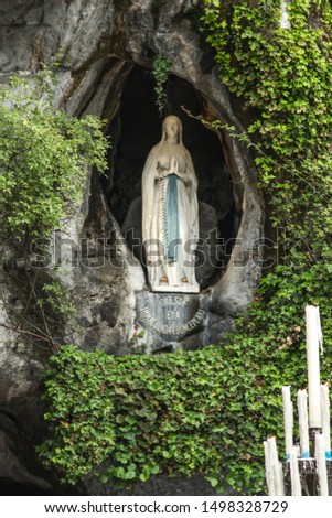 Statue of Our Lady of Immaculate Conception with a rosary in the Grotto of Massabielle in Lourdes, France