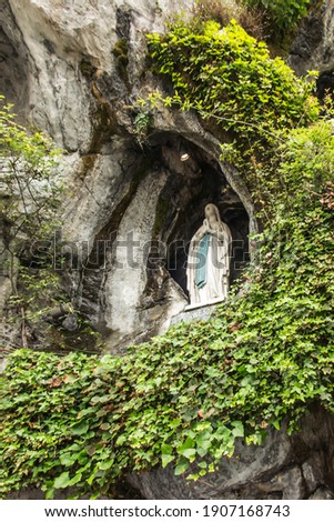 Statue of Our Lady of Immaculate Conception with a rosary in the Grotto of Massabielle in Lourdes, France