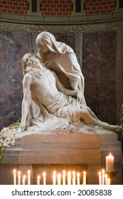 Statue Pieta in chapel of romanesque St. Gereon church in Cologne with candles and candlelight.
