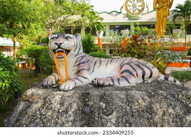 Statue of a sacred tiger holding a flower necklace in its mouth in the Wat Tham Suea, the Tiger Cave Temple of Krabi in the south of Thailand