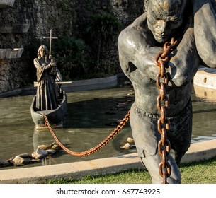 Statue Of A Slave Carrying A Boat Using A Chain. Public Statue In A Park Of The City Of Santana De Parnaíba, In São Paulo, Brazil.