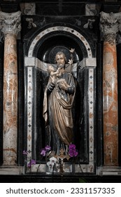Statue of St. Joseph, inside a small chapel, holding baby Jesus in his arms