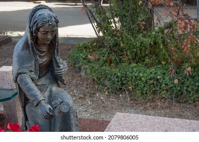 statue of a woman laying a flower on a grave