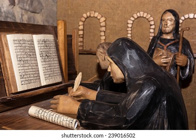 Statues of monks in the monastery. Monk rewrites the book.