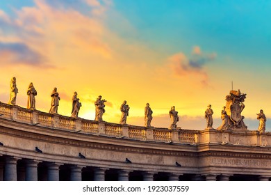 Statues on colonnades on St. Peter's Square in Vatican, Rome against colorful sunset.