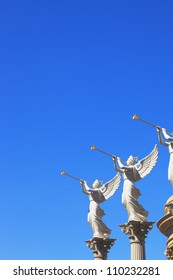 The statues of winged troubadours against the blue sky decorated capitals of the columns.
