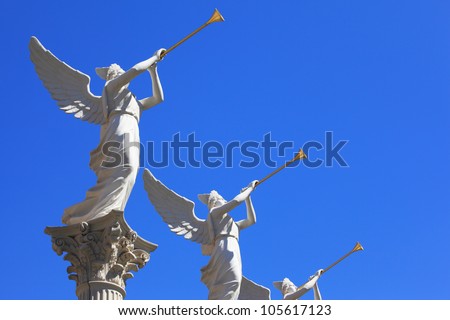 The statues of winged troubadours against the blue sky decorated capitals of the columns.