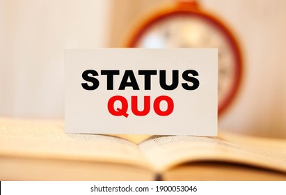 STATUS QUO On The Background Of A Clock On A Business Card