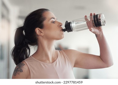 Stay active and stay hydrated. a young athlete drink water while at the gym.