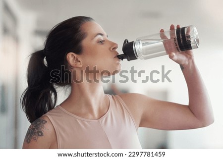 Stay active and stay hydrated. a young athlete drink water while at the gym.