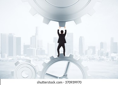 Stay Afloat Concept With Businessman And Gears At City Background