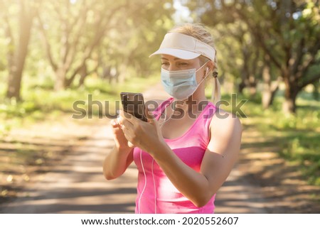 Stay in fit during quarantine. A sportive young woman is jogging outdoor, she have protective mask on face. Running alone of the Corona Virus or Covid-19.