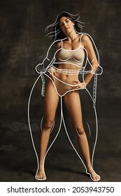 Stay fit and improve health. Young girl with perfect body shape in underwear isolated over dark background. Drawings of overweight lines around body. Concept of healthy eating, dieting, wellness.