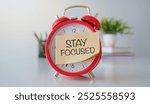 Stay focused symbol. Business, support, motivation, psychological stay focused concept. STAY FOCUSED on a yellow sticker on a red alarm o