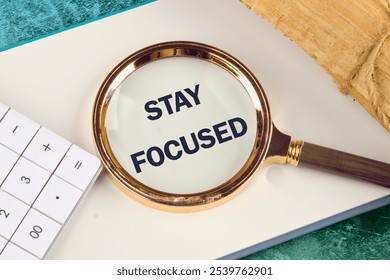 STAY FOCUSED write on a blank page of a business notebook through a magnifying glass, a conceptual photo. - Powered by Shutterstock