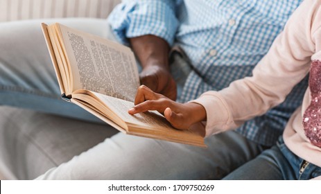 Stay home activities. Lillte African American girl reading fairy tale with her granddad, closeup of hands holding book. Panorama