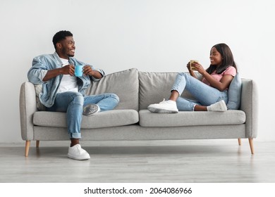 Stay At Home Date. Beautiful African American Couple Drinking Coffee And Talking, Resting On The Couch Indoors At Home In Living Room, Relaxing Enjoying Company Of Each Other Spending Weekend Together