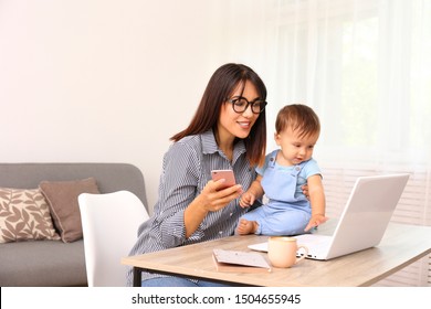 Stay at home mom working remotely on laptop while taking care of her baby. Young mother on maternity leave trying to freelance by the desk with toddler child. Close up, copy space, background. - Shutterstock ID 1504655945