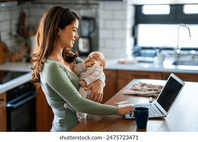 Stay at home mom working remotely on laptop while taking care of her baby. Global work on computer - Powered by Shutterstock