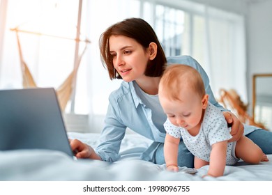 Stay At Home, Mom Works Remotely On Laptop, Taking Care Of Her Baby. A Young Mother On Maternity Leave Tries To Work In Bed With A Small Child. Close Up, Copy Space, Background.