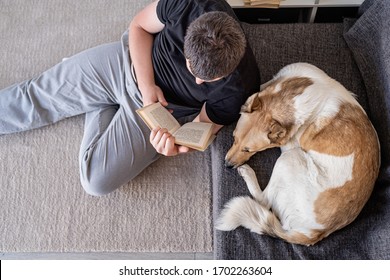 Stay home. Pet care. Young man reading sitting on the floor at home with his dog