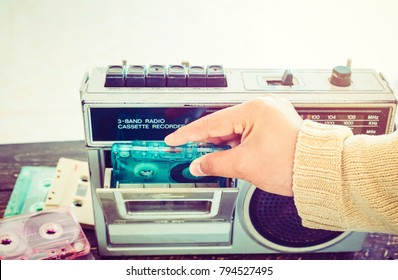 Stay at home retro lifestyle - Woman hand holding tape cassette with cassette player and recorder for listen music - vintage color tone effect.