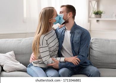 Stay at home romance. Young married couple kissing in protective medical masks