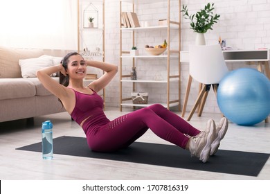 Stay At Home Sports. Joyful Hispanic Girl Doing Abs Workout In Light Room