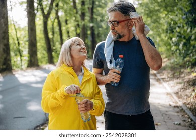 Stay hydrated. With bottle of water after jogging. Senior couple together outdoors at nature. - Powered by Shutterstock