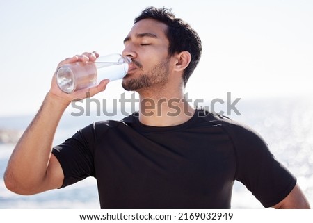 Stay hydrated. Cropped shot of a handsome young male athlete hydrating during his workout on the beach.