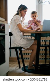 Stay At Mother Home Sitting In Kitchen And Getting Work Done While Her Baby Girl Helping Her.