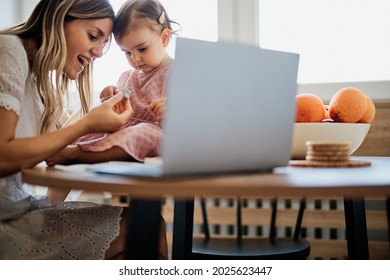 Stay At Mother Home Sitting In Kitchen And Getting Work Done While Her Baby Girl Helping Her.