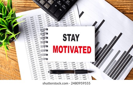 STAY MOTIVATED text on a notebook on chart with calculator and pen .  - Powered by Shutterstock