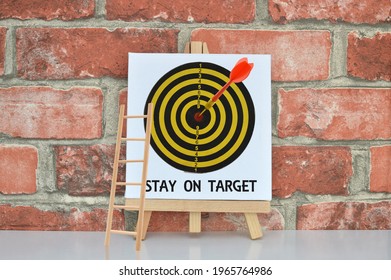 Stay on Target Canvass Board with Dart in front of brick wall
