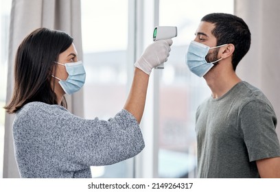 Stay One Step Ahead Of Sickness With Consistent Symptom Management. Shot Of A Young Woman Taking Her Husbands Temperature While Recovering From An Illness At Home.