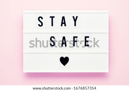 STAY SAFE written in light box on pink background. Healthcare and medical concept. Top view, copy space. Quarantine concept.