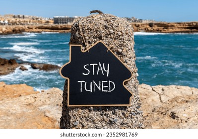 Stay tuned symbol. Concept words Stay tuned on beautiful black chalk blackboard on a beautiful beach stone background. Business, support, motivation, psychological and stay tuned concept. Copy space.