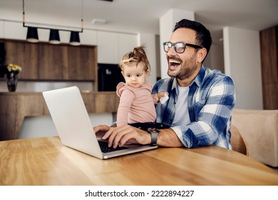 A Stay-at-home Father Works On A Laptop From Home While His Baby Girl Helps Him Finish The Task.