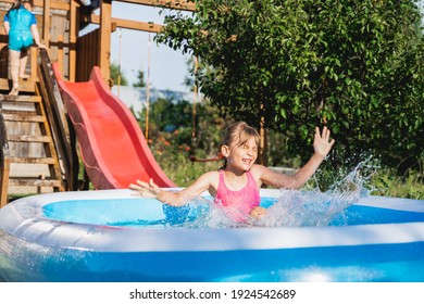 Staycation At Home. Little Girl In Swimsuit Rolls Down Slide Into Inflatable Rubber Pool. Swim Activity In Backyard Of Country House. Summer,relaxation On Isolation,quarantine Of Coronavirus Covid-19.