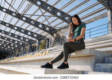 Staying Active: Brunette with Smartphone in Sports Venue - Powered by Shutterstock