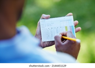 Staying below par. Rearview shot of a young golfer marking his scorecard. - Powered by Shutterstock