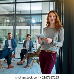 Staying Current And Connected. Portrait Of A Young Creative Standing In An Office With Colleagues In The Background.