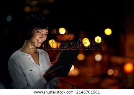 Staying up to date with all hour connectivity. Shot of an attractive young woman using a digital tablet outside in the city at night.