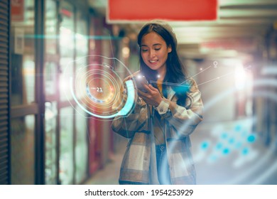 Staying up to date with technology in a fast moving world, concept. A young Asian woman is using an innovative future technology to view her phone data and functions in holographic display around her 