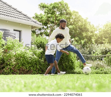 Staying fit while having fun. Shot of a father and son playing soccer together outdoors.