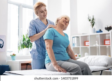 Staying healthy. Pleasant grey haired woman receiving neck massage while visiting the hospital - Powered by Shutterstock