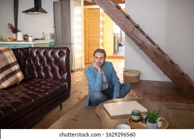 Staying At Home. A Bored Man Sitting On The Floor At His Appartment